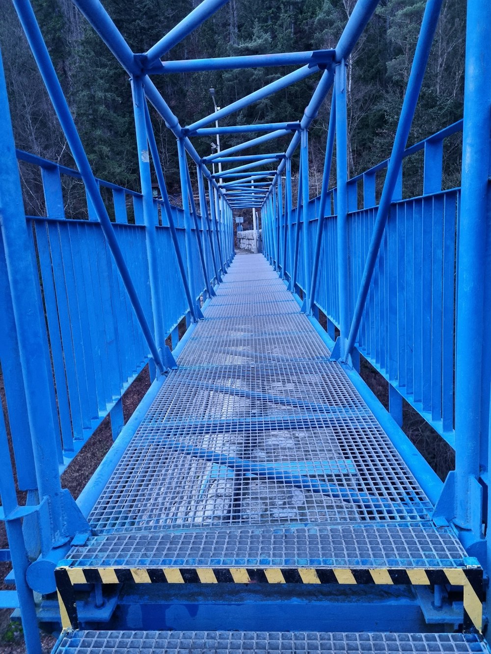 a blue metal bridge with a yellow stripe on the bottom