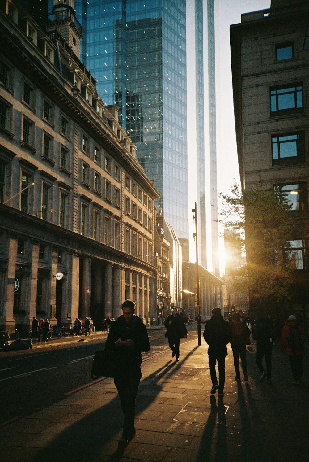 a group of people walking down a street next to tall buildings