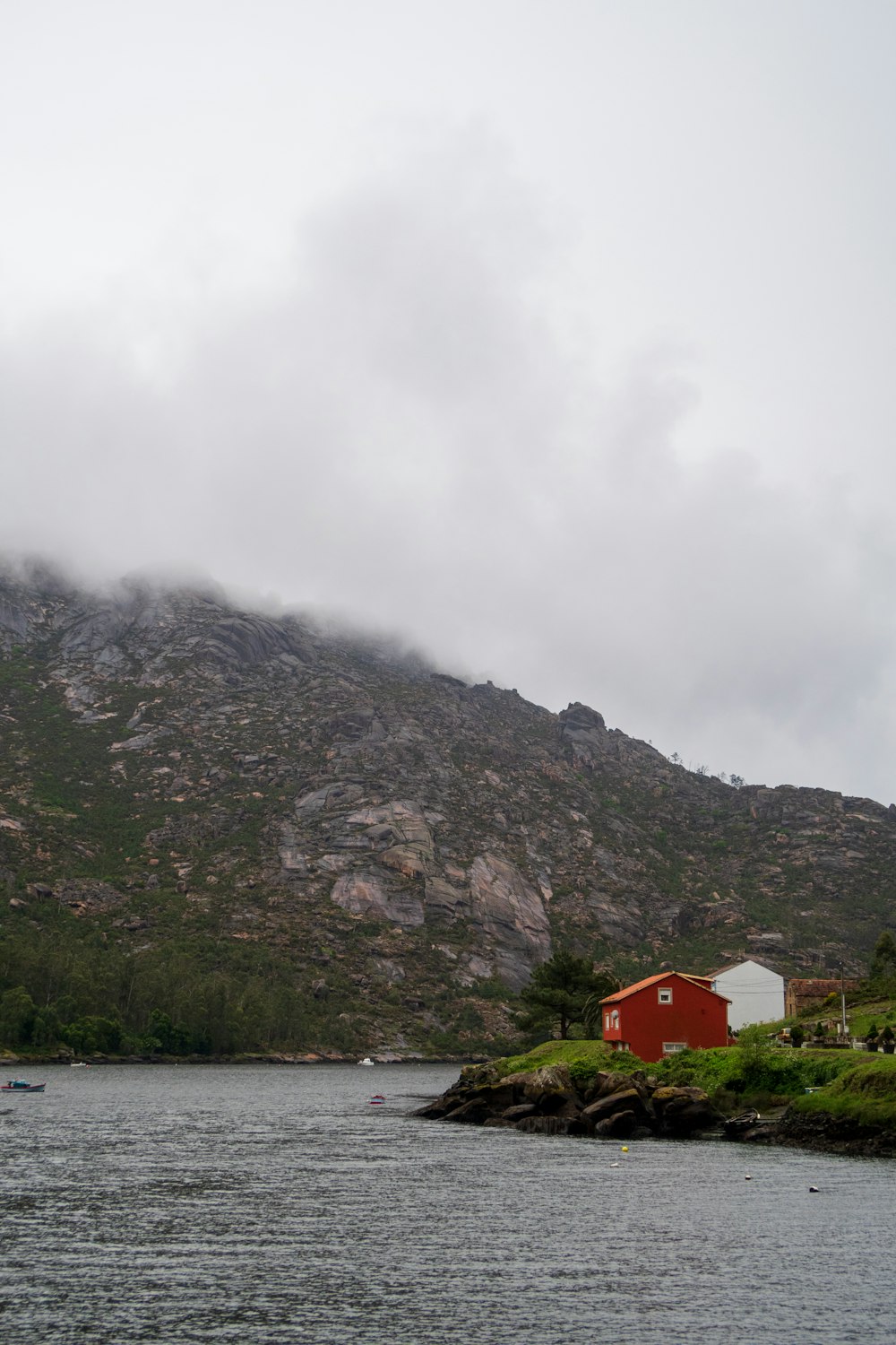 a red house on a small island in the middle of a lake