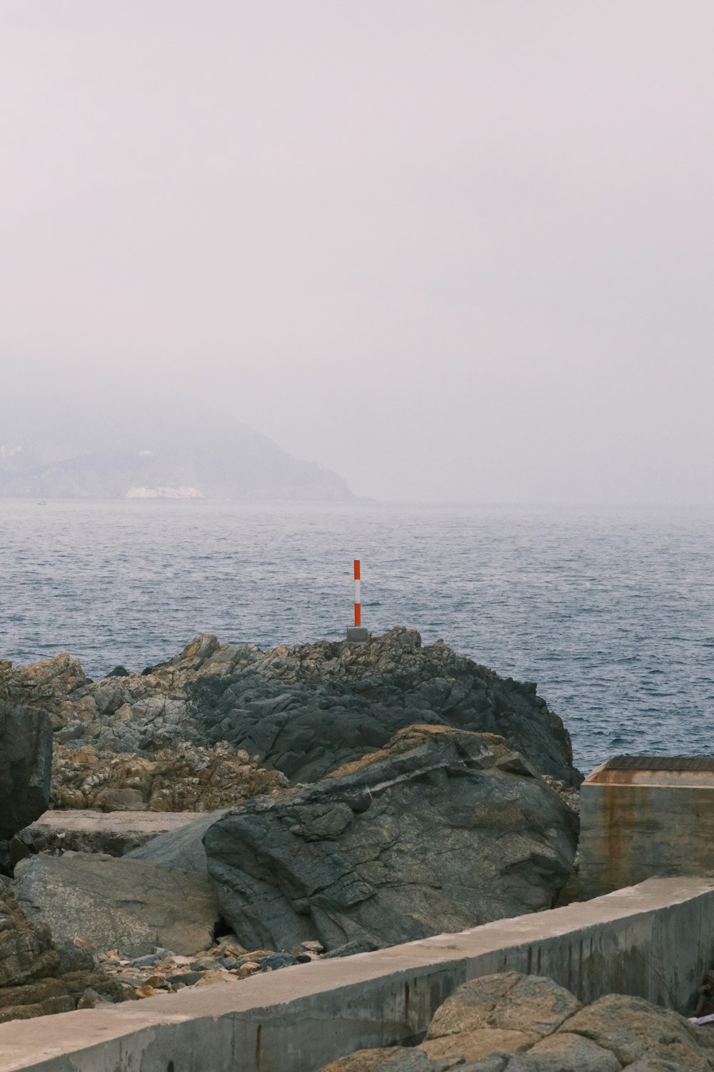 a lighthouse on a rocky shore with a body of water in the background