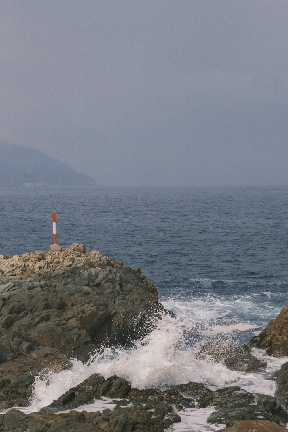 a red and white light house sitting on top of a rocky shore