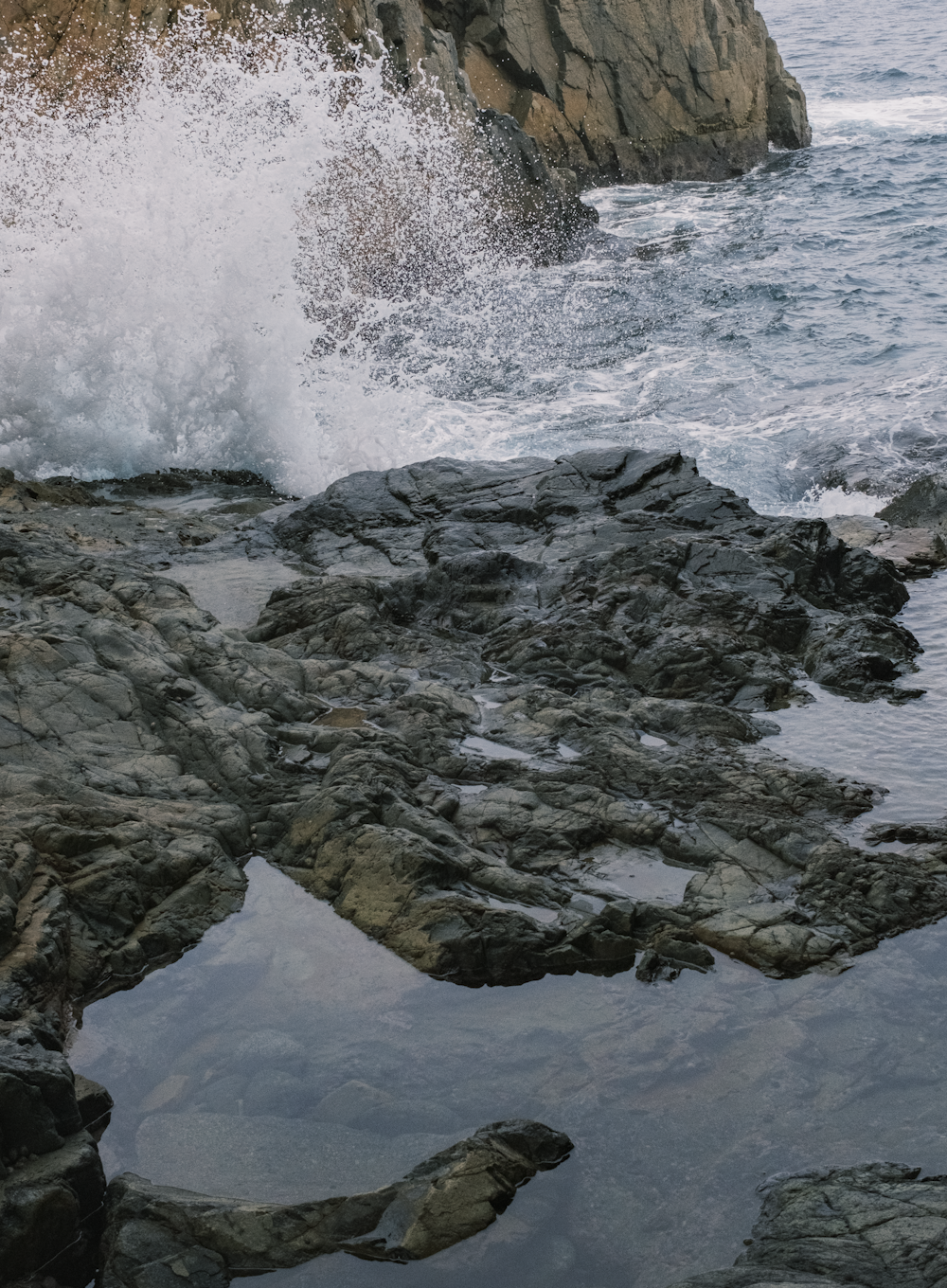 a large wave crashing into a rocky shore