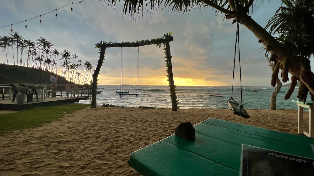 a bench sitting on top of a sandy beach next to the ocean