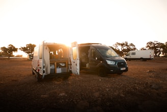 a couple of vans that are parked in the dirt