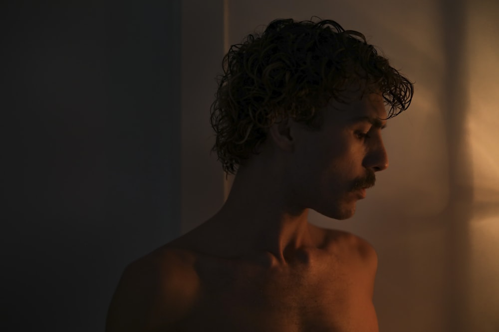 a man with curly hair standing in a dark room