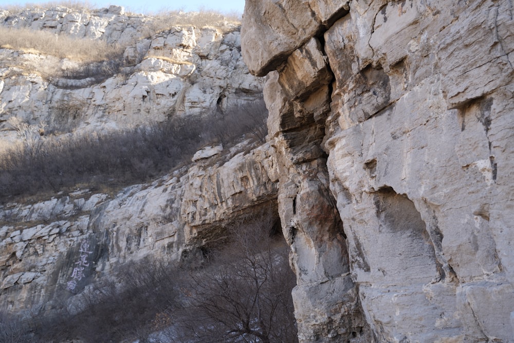 a person climbing up a cliff with a snow covered mountain in the background