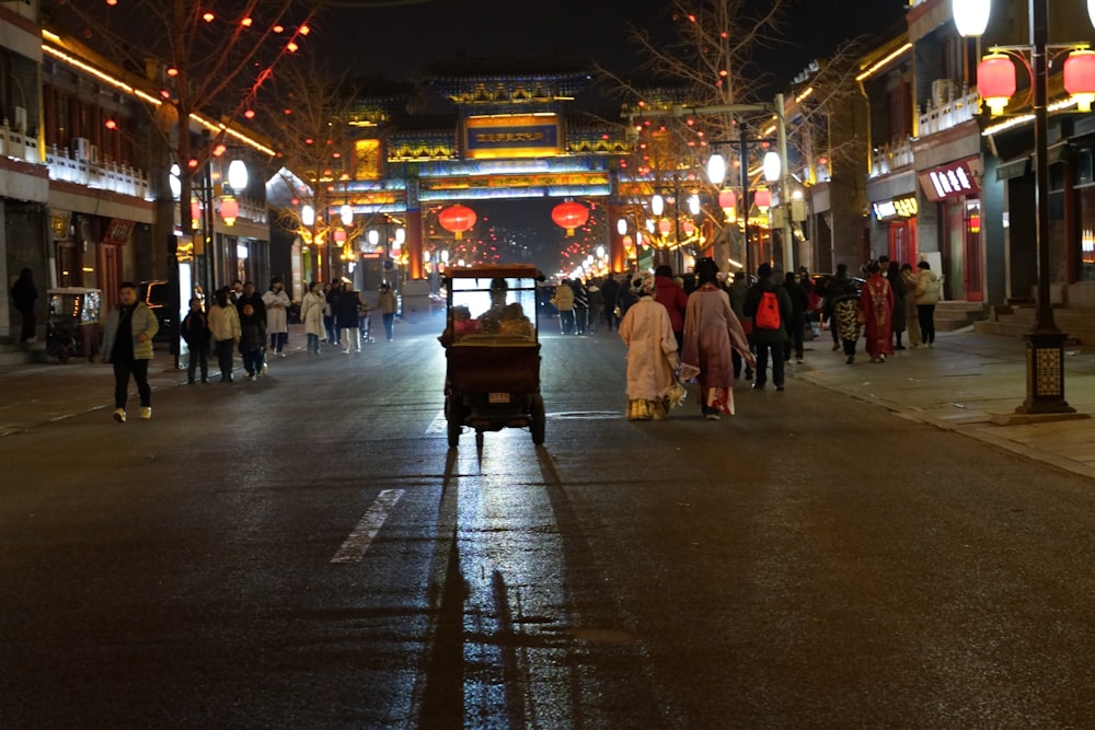 a busy city street at night with people walking on the sidewalk