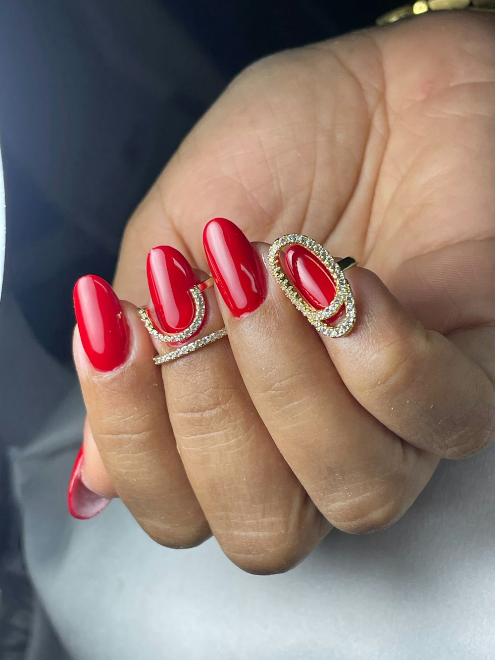 a woman's hand with a red manicure and a gold ring