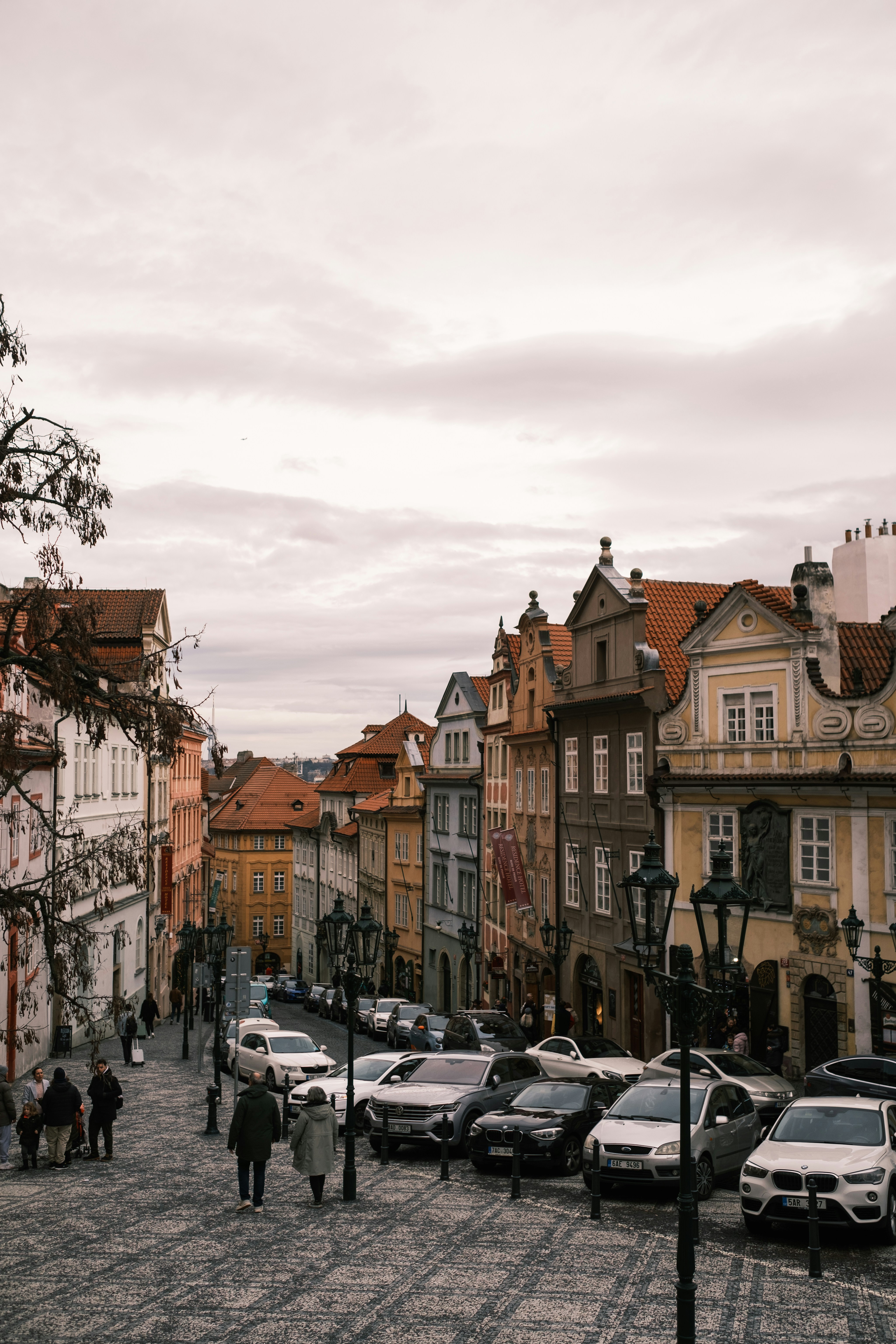 a group of people walking down a street next to parked cars