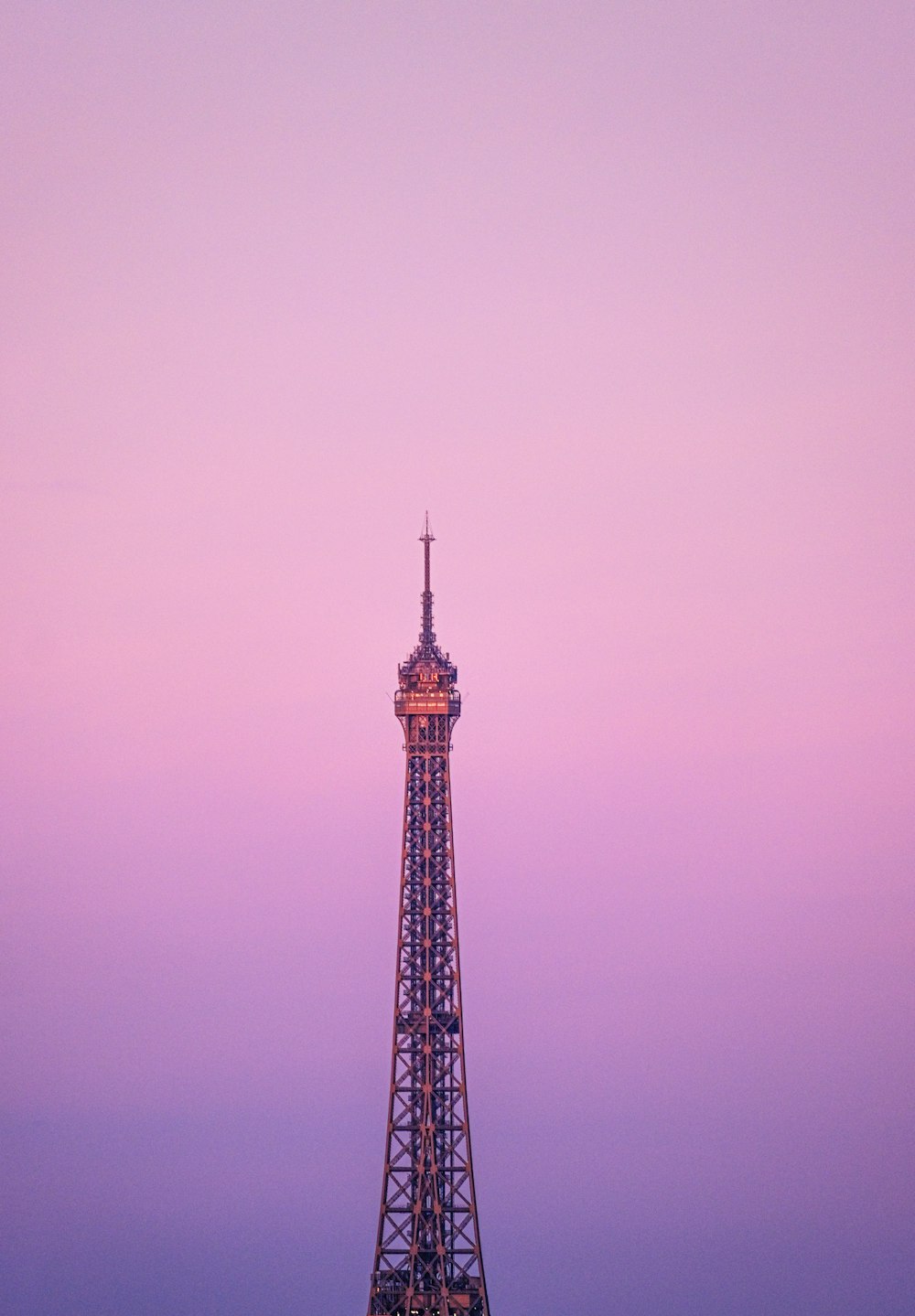 the eiffel tower is lit up at dusk