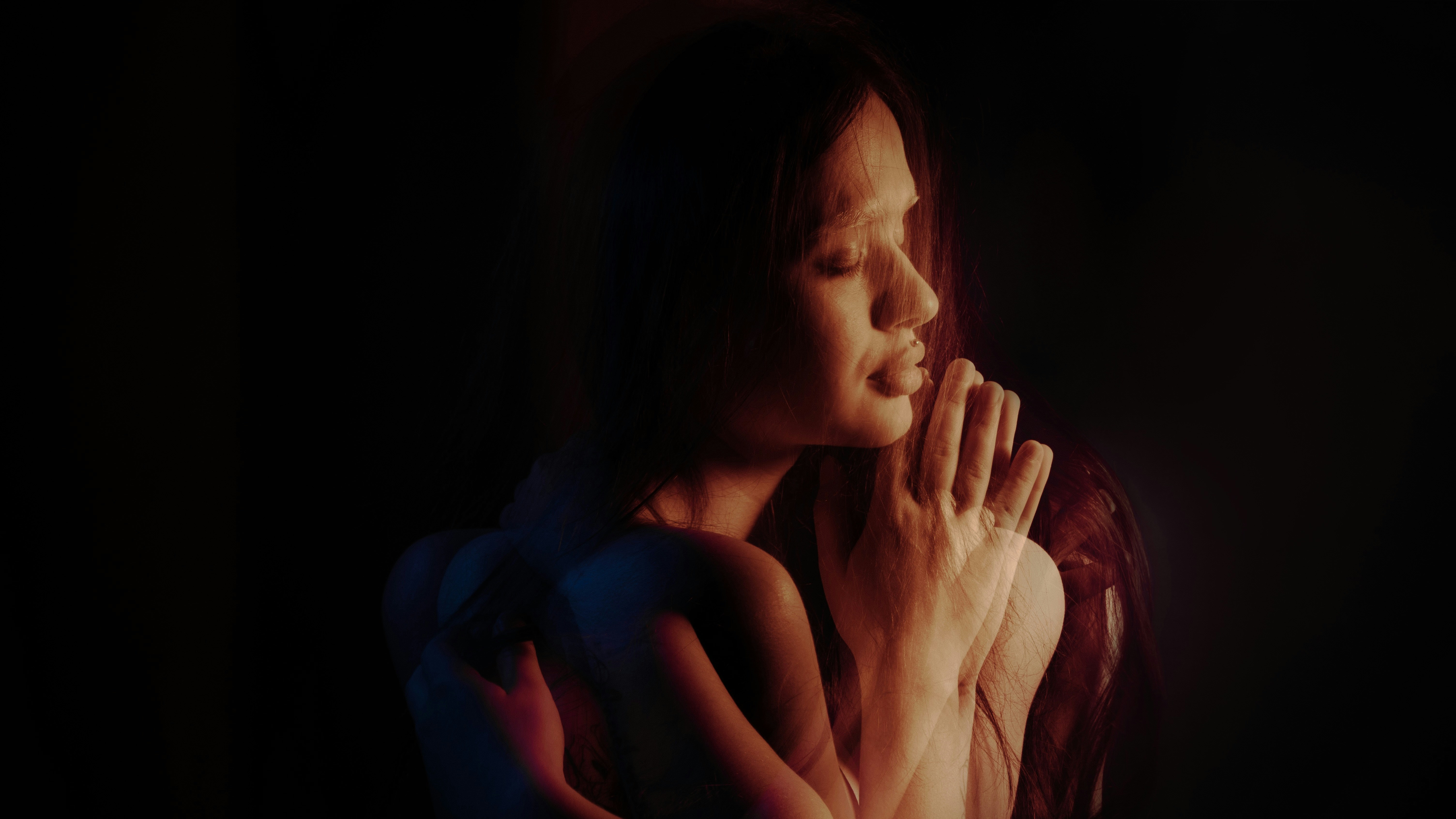 a woman holding her hands together in prayer