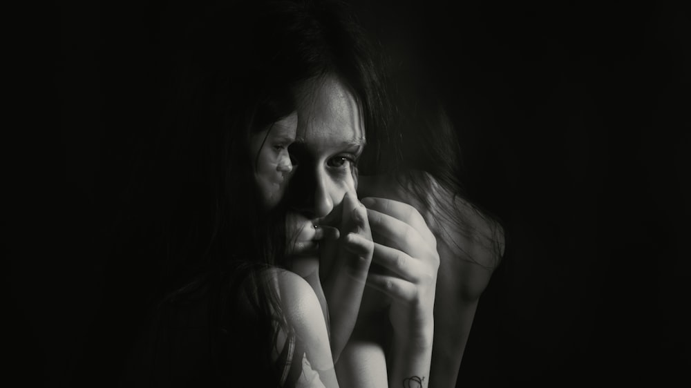 a black and white photo of a woman with her hands on her face