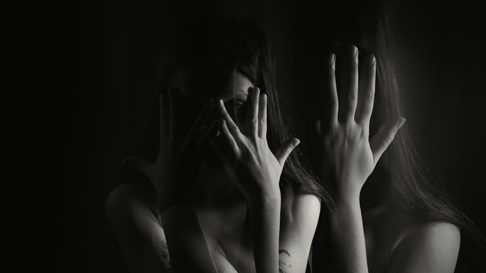 a black and white photo of two women covering their faces