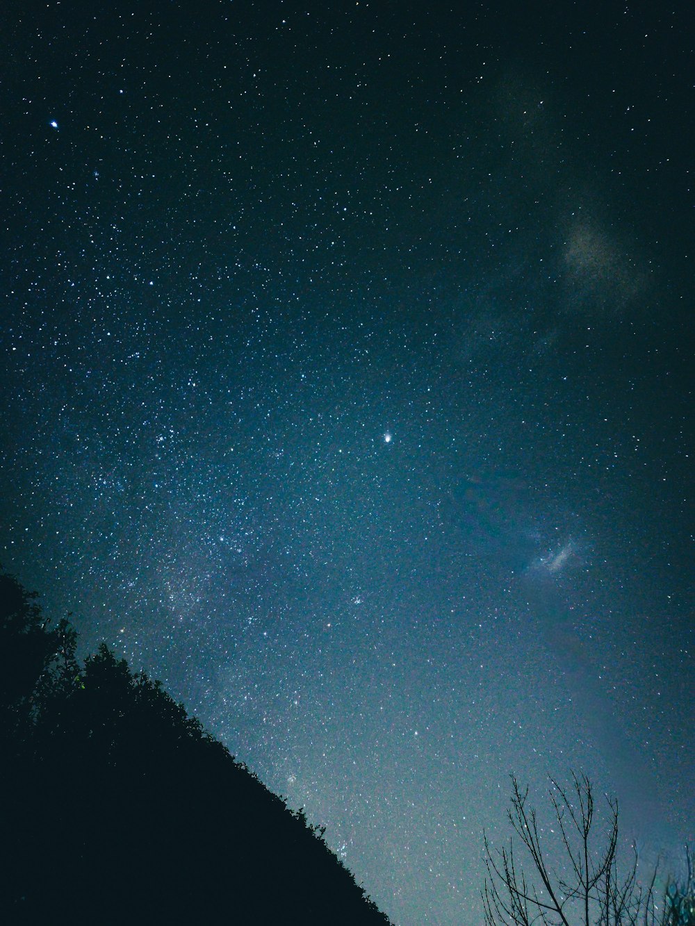 the night sky with stars above a hill