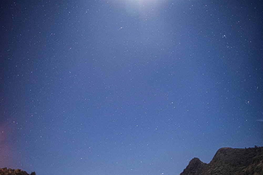 a full moon shines in the sky above a mountain range