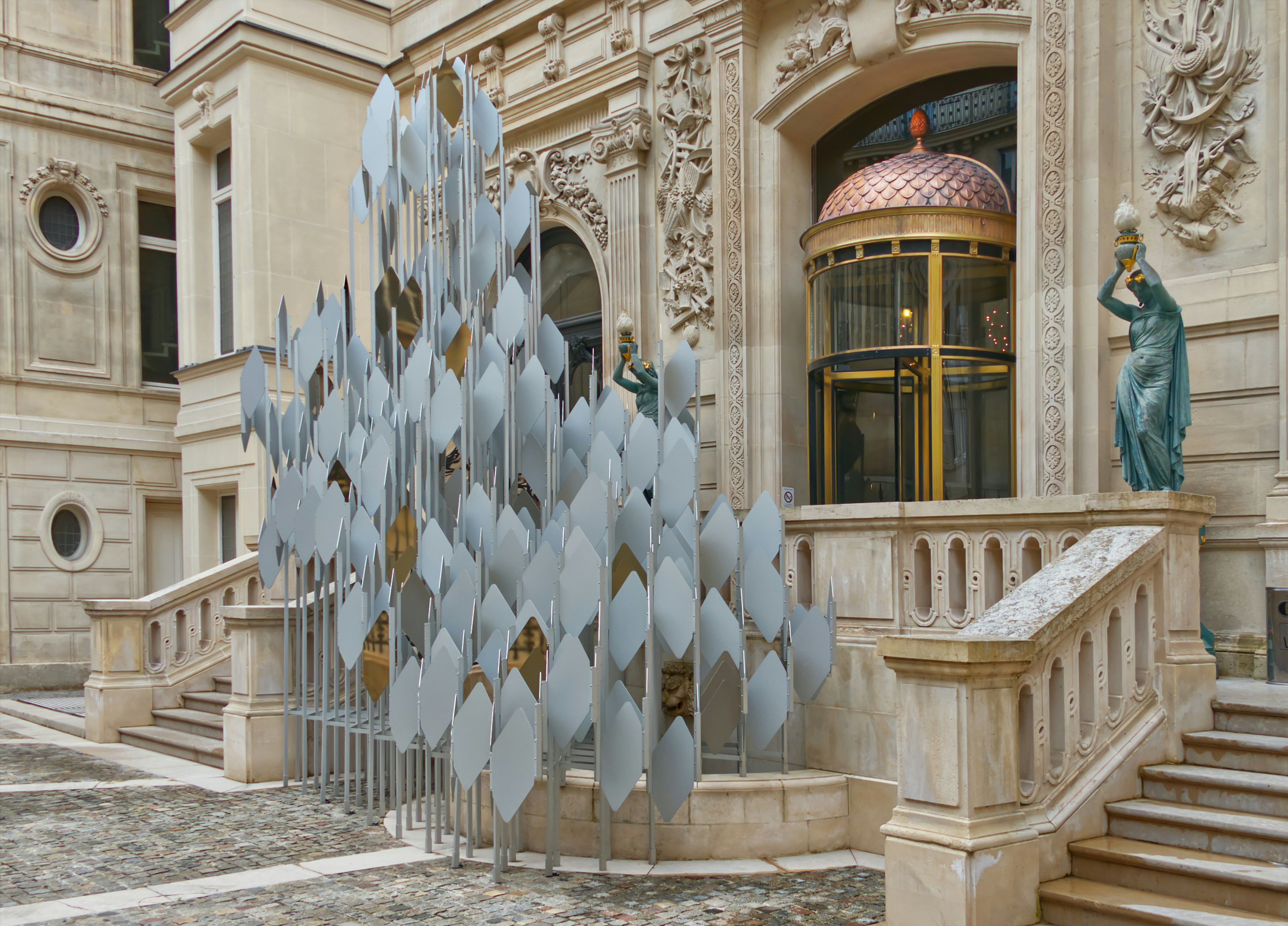 Sculpture mobile dans la cour de l’hôtel de Gunzburg. Vincent Mauger est l’artiste auteur de cette œuvre. Elle évoque, d’une façon très stylisée, une forme végétale telle une vigne vierge, un lierre ou une glycine. Elle est composée de 178 tubes en aluminium, de 383 écailles en aluminium et en inox poli miroir.