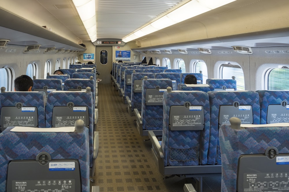 the inside of a passenger train with blue seats