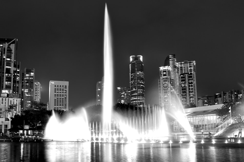 a black and white photo of a fountain in a city