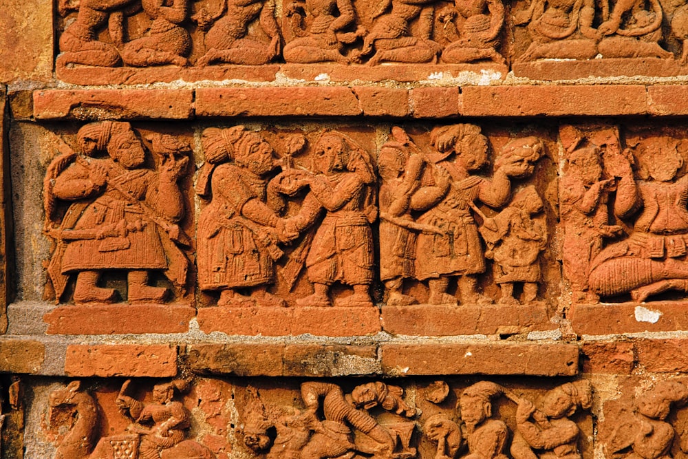 a brick wall with a bunch of carvings on it