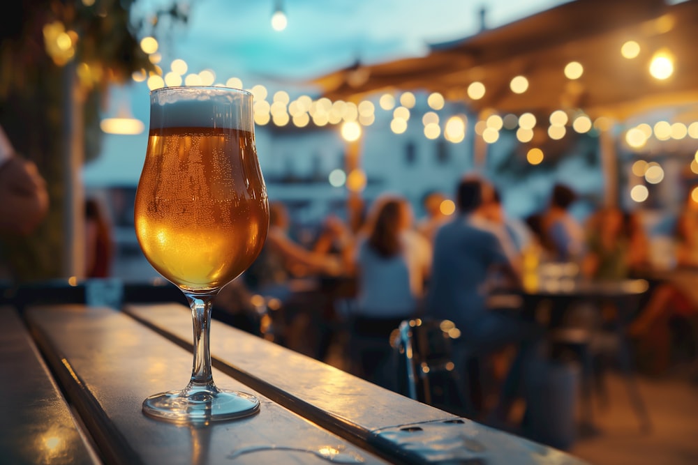 a glass of beer sitting on top of a wooden table