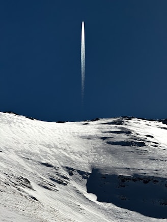 a jet flying over a snow covered mountain under a blue sky