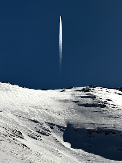a jet flying over a snow covered mountain under a blue sky