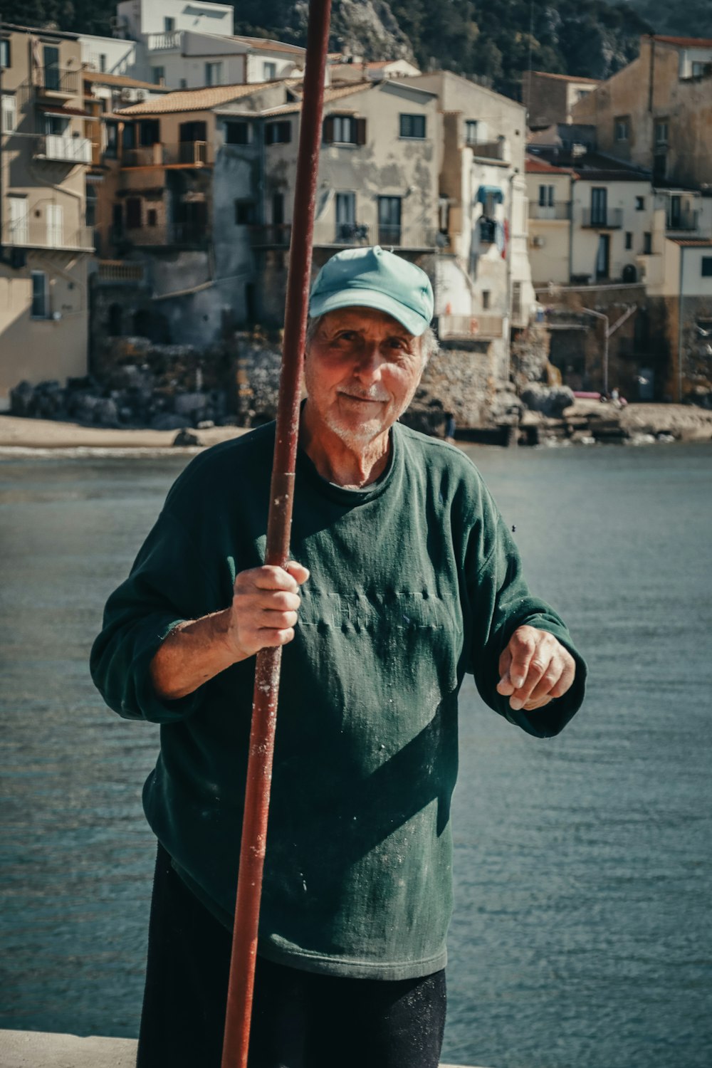 a man standing next to a body of water holding a pole