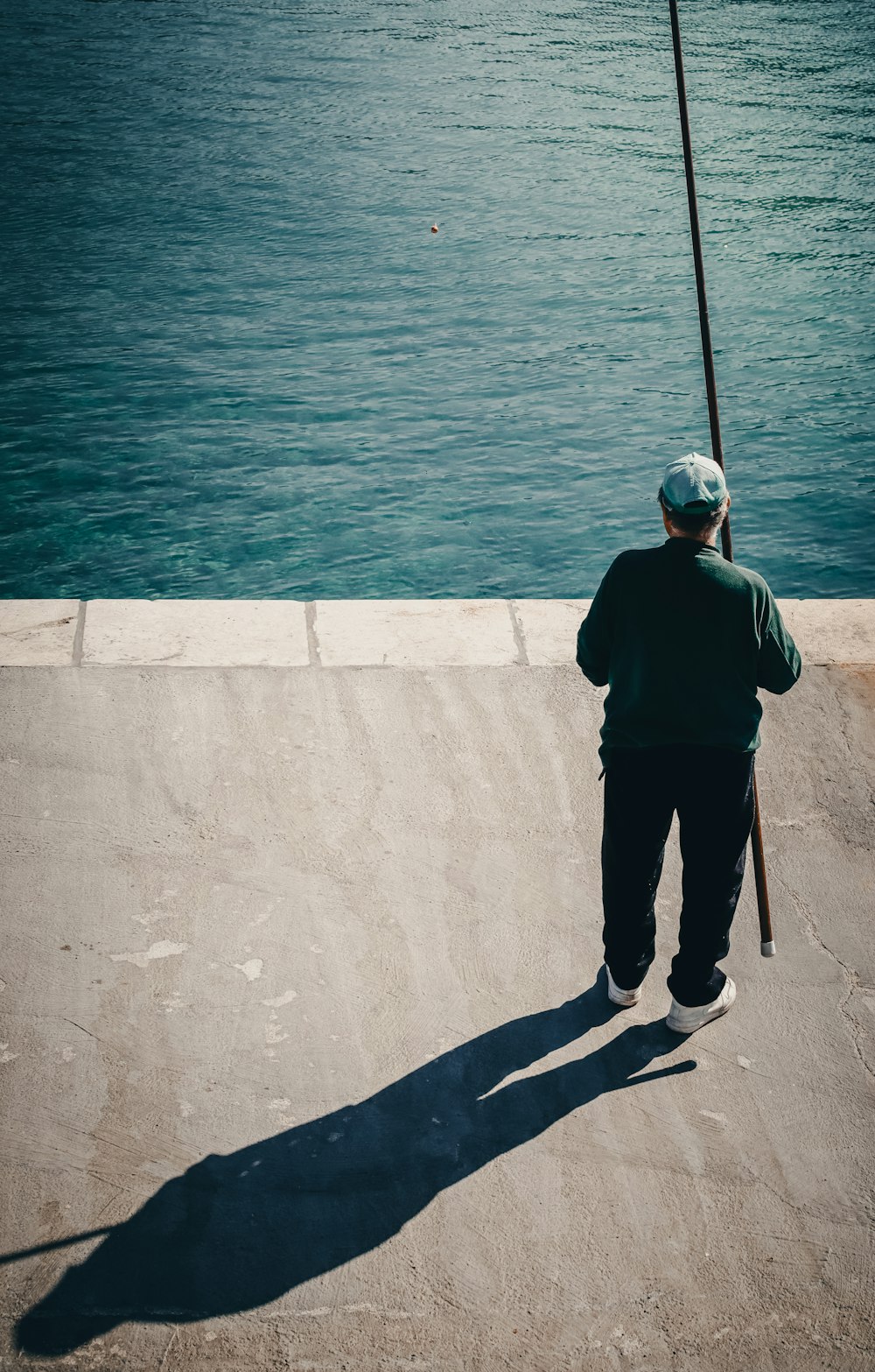 una persona in piedi su un molo con un palo