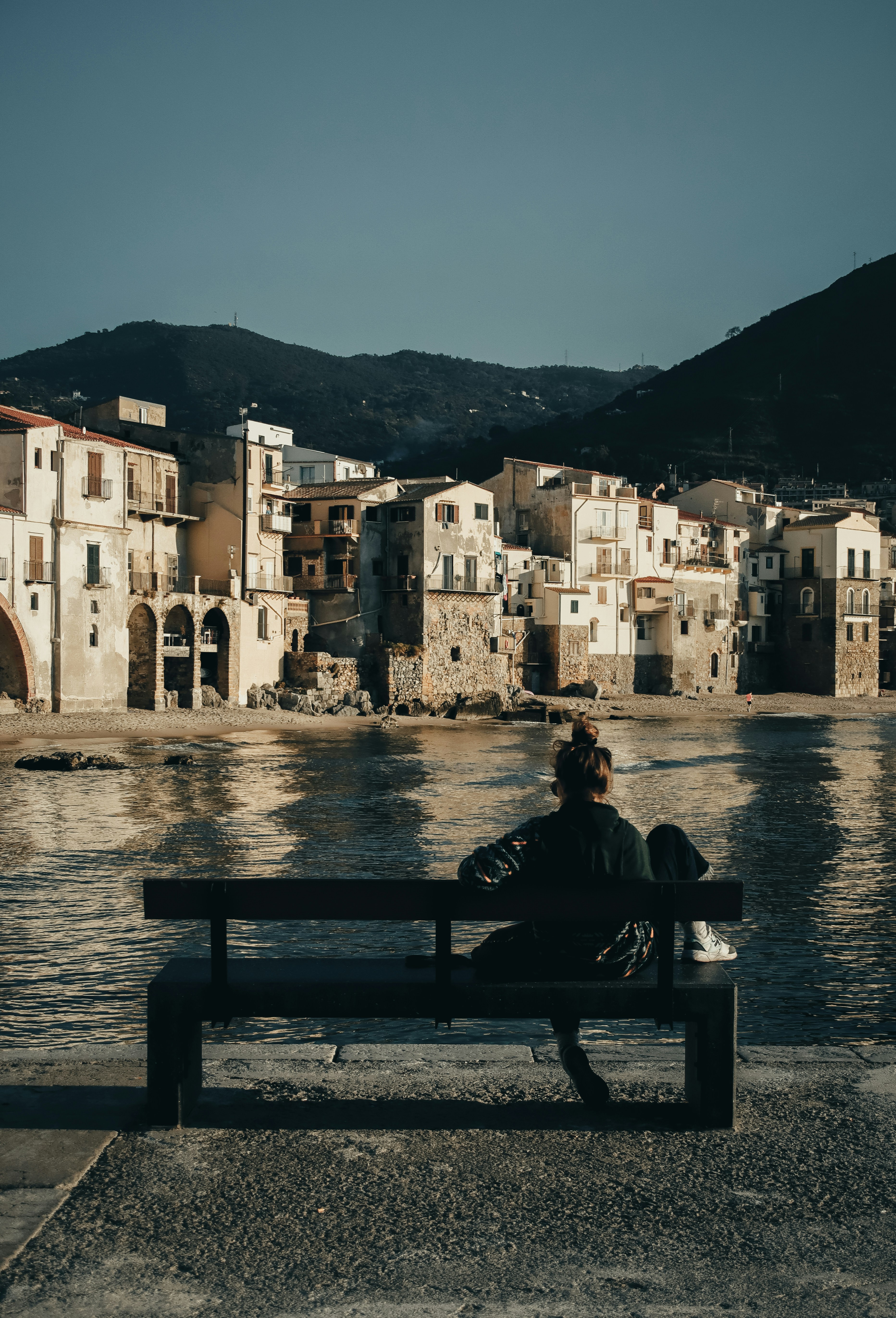 Two people sitting on a bench near a body of water photo – Free Beach ...