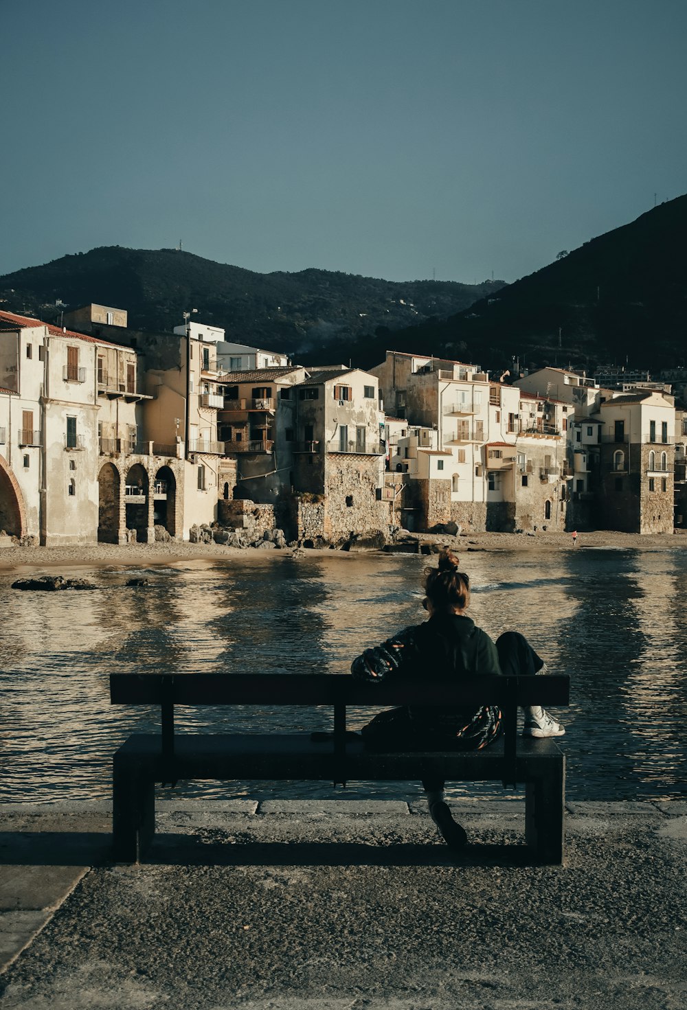 two people sitting on a bench near a body of water