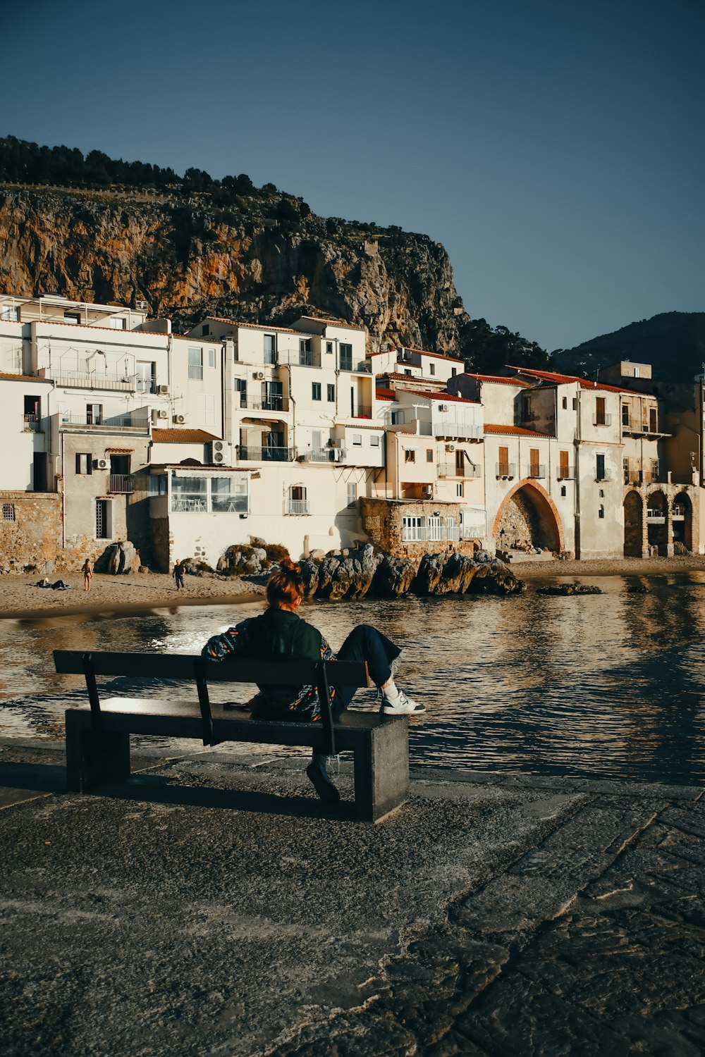 a person sitting on a bench near a body of water