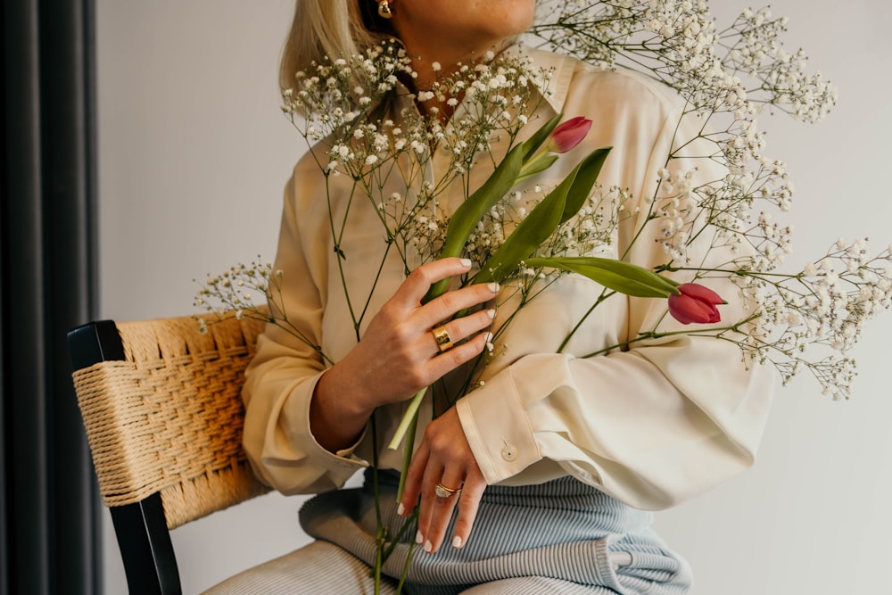 a woman sitting on a chair holding a bouquet of flowers