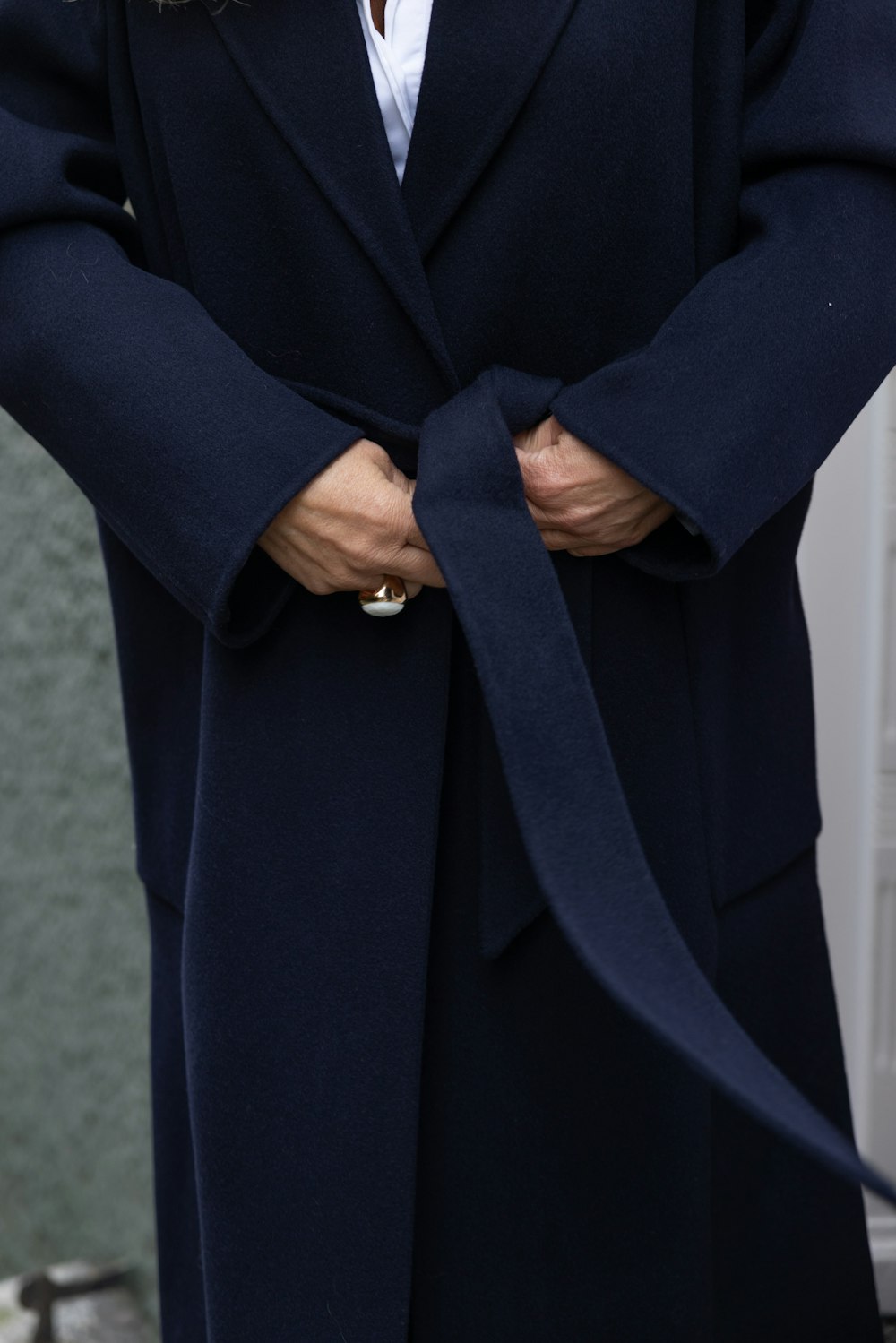 a woman wearing a coat with a tie around her waist