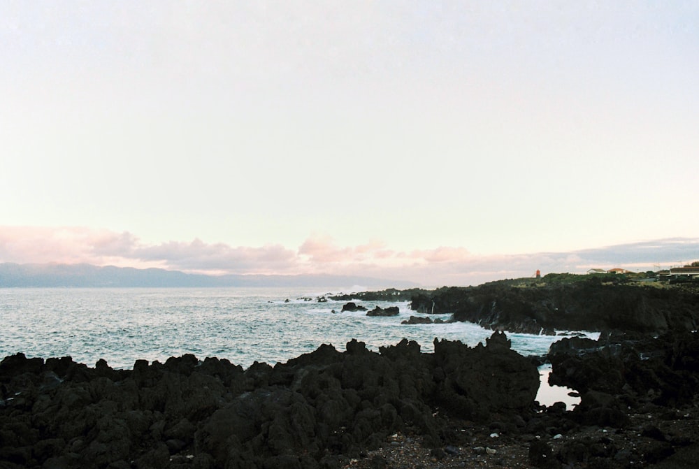une personne debout sur une plage rocheuse à côté de l’océan