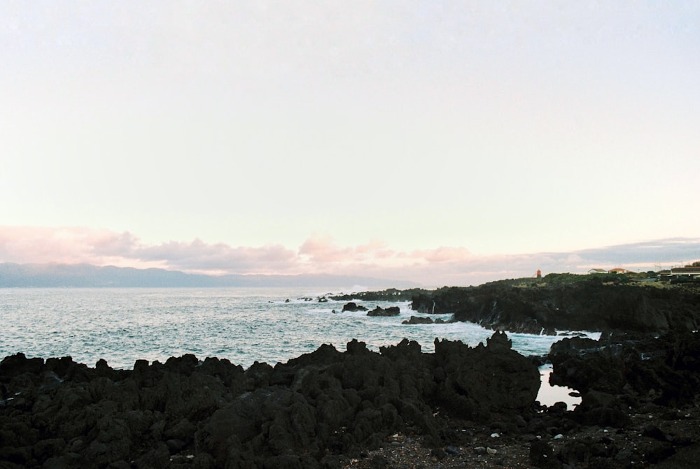 a person standing on a rocky beach next to the ocean