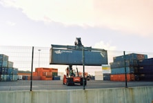 a forklift is moving a large container behind a fence