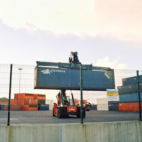 a forklift is moving a large container behind a fence