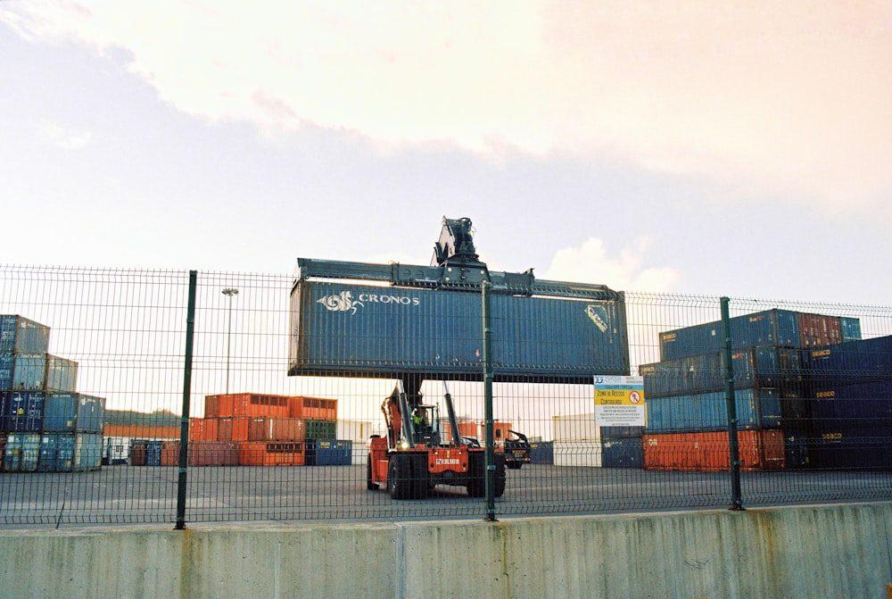 a forklift is moving a large container behind a fence