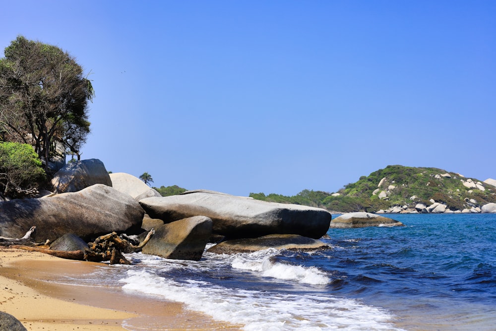 a sandy beach with large rocks and water