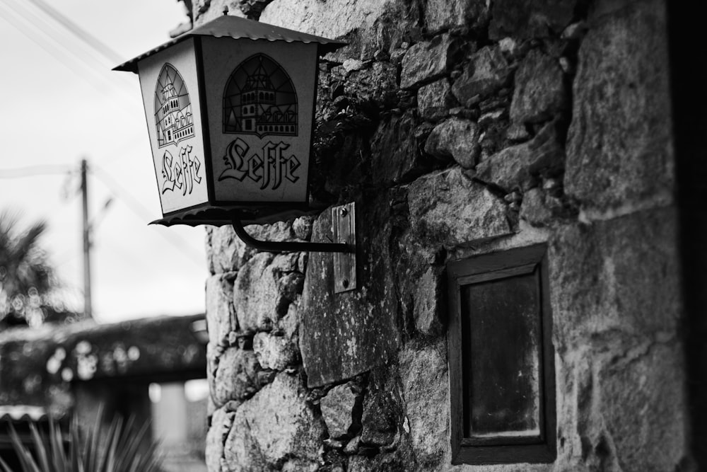 a black and white photo of a light on a stone wall