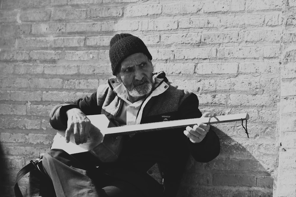 a black and white photo of a man sitting on a brick wall