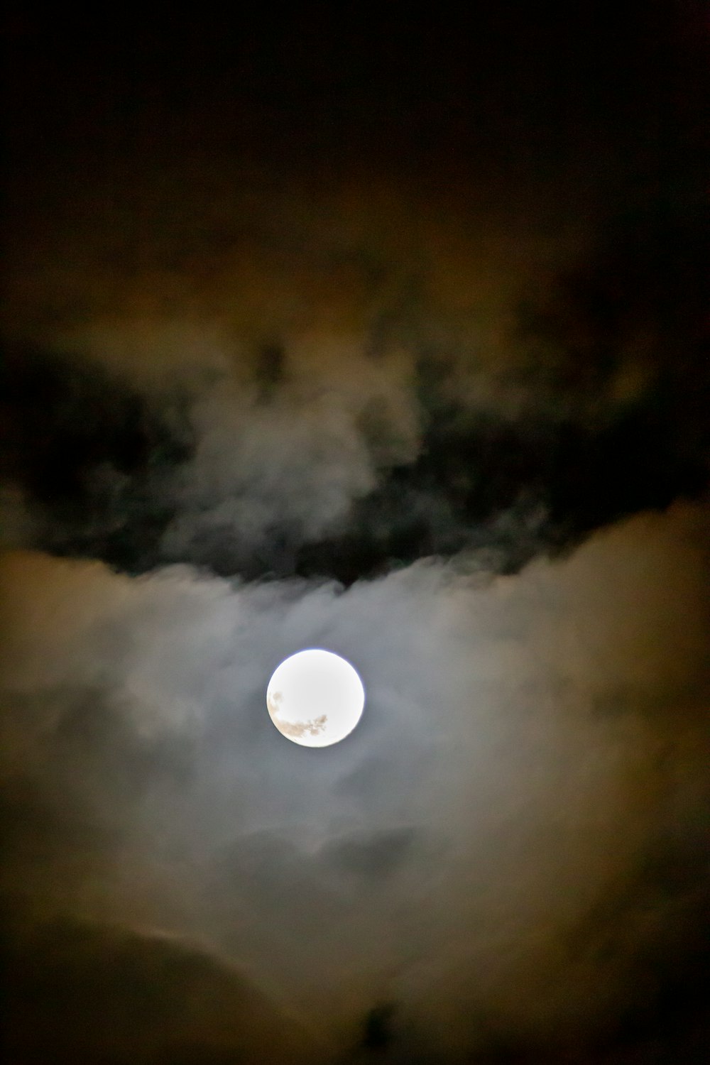 a full moon is seen through the clouds