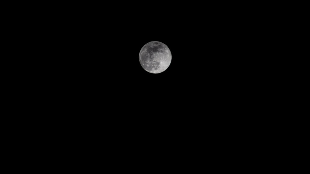 a full moon is seen in the dark sky