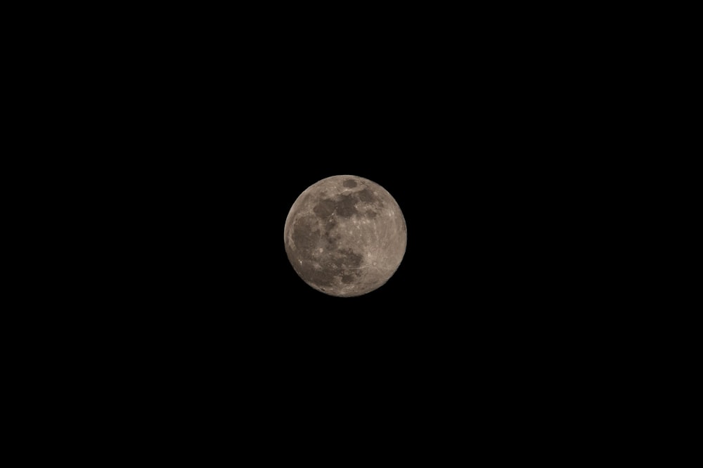 uma lua cheia é vista no céu escuro
