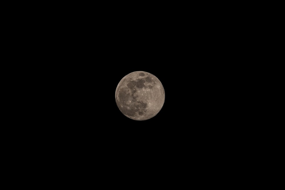 a full moon is seen in the dark sky