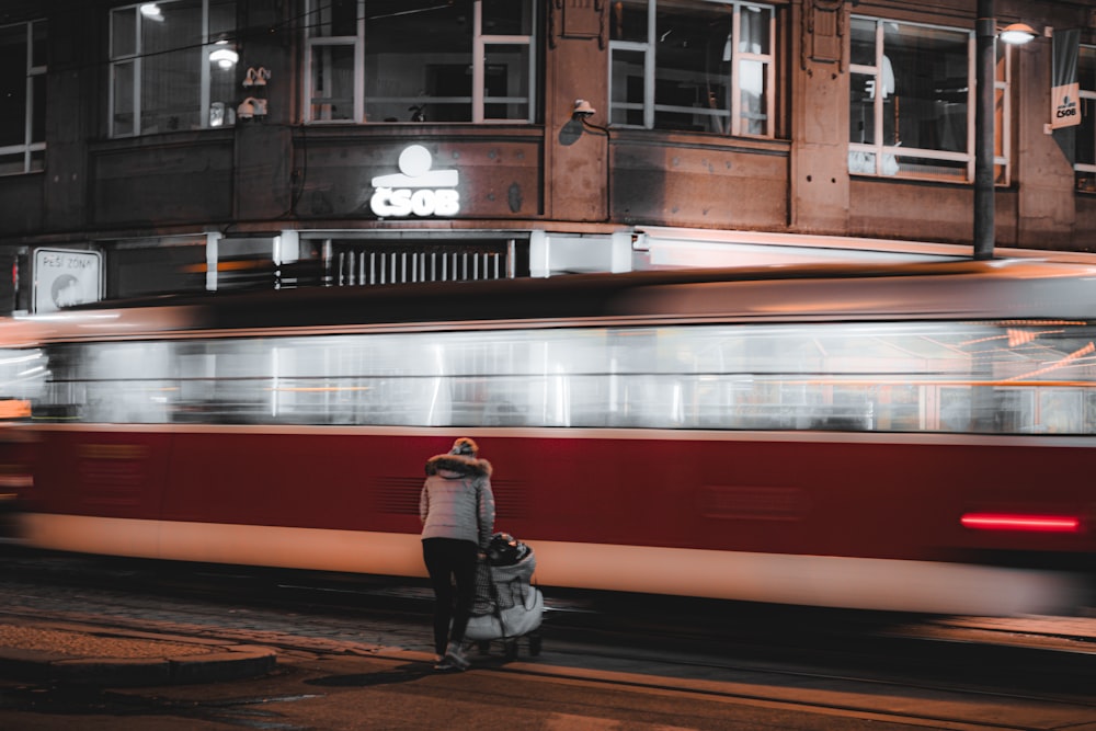 a red and white train traveling past a tall building