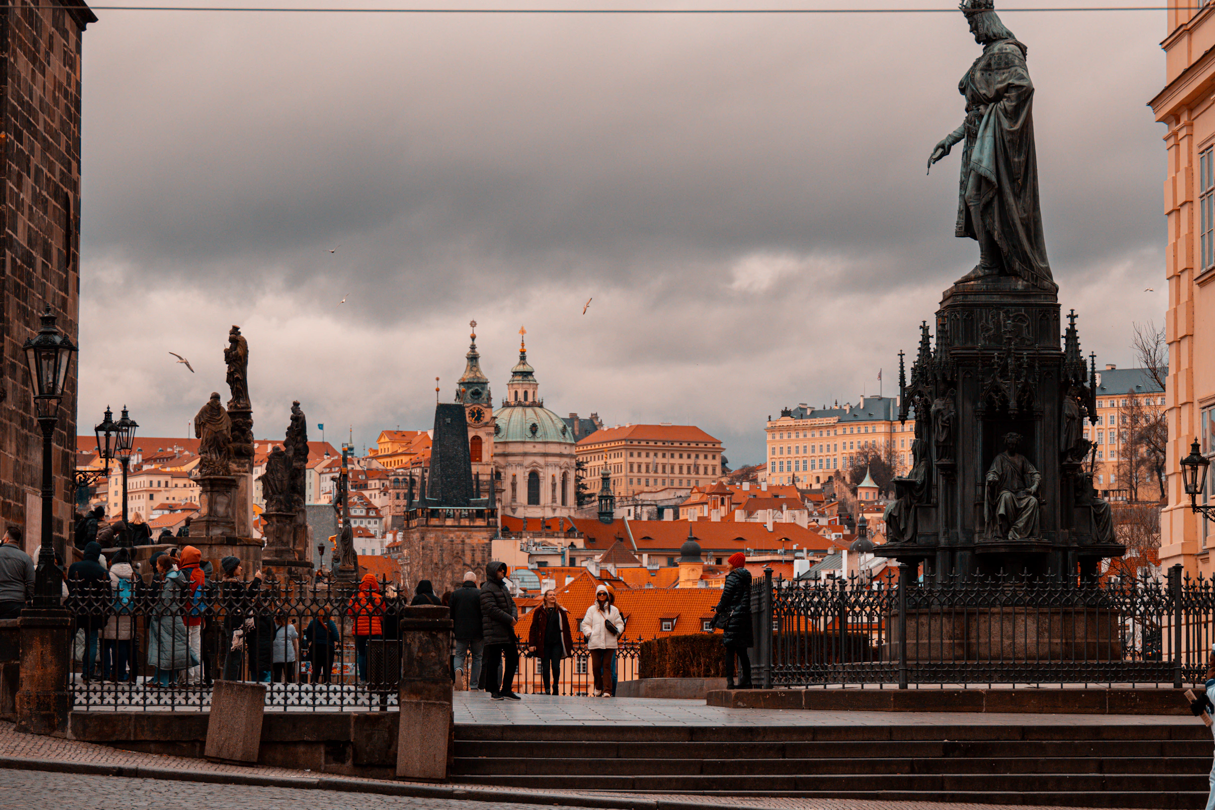 Crowds on a historic stone bridge with statues and city spires