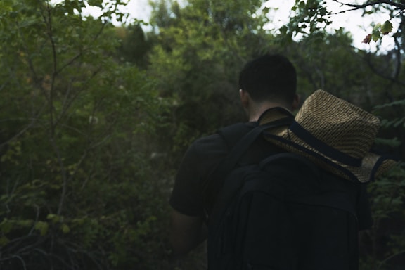 a man walking through a forest with a backpack