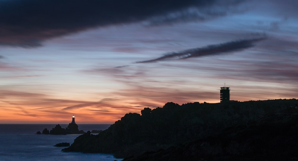 a lighthouse on top of a hill next to a body of water