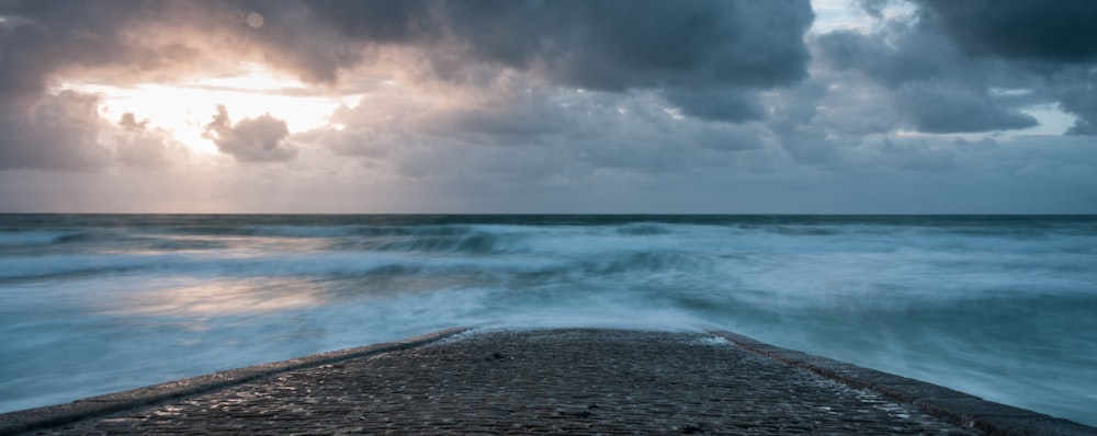 O sol está brilhando através das nuvens sobre o oceano